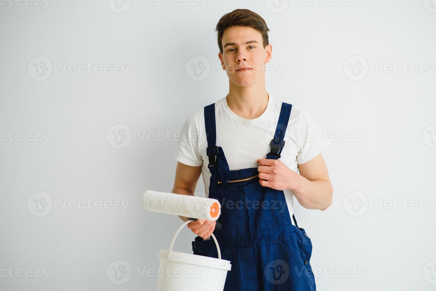 The painter is painting a wall in a room with a roller. photo