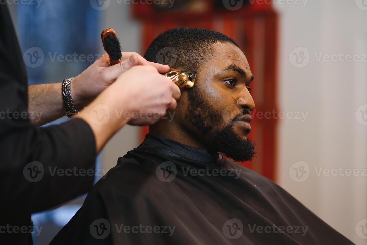 Closeup of process of trimming of hair in barber shop. Qualified barber keeping clipper in hands and correcting shape of hair to male client sitting on chair. Concept of haircut and shaving. photo