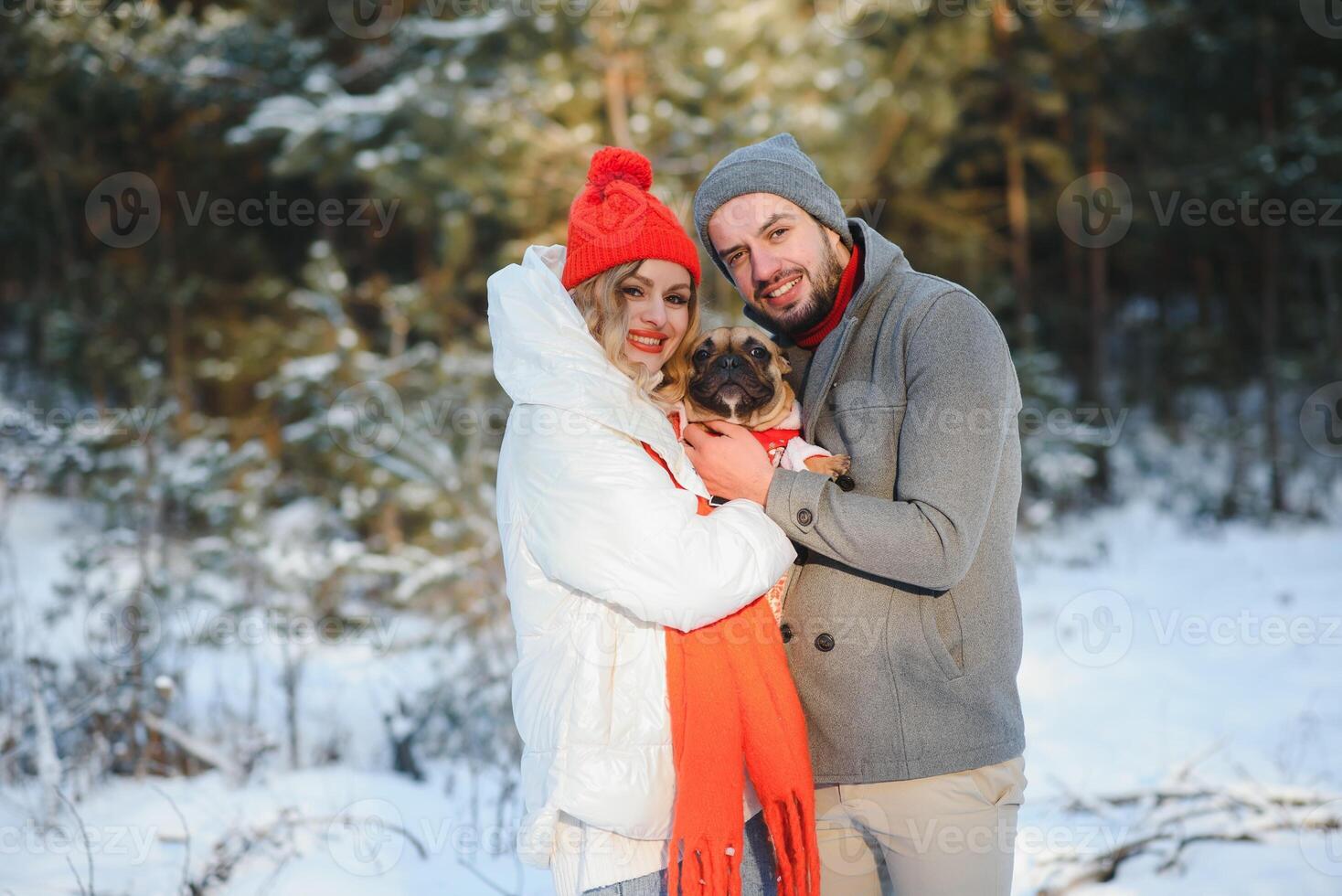 Young couple in love with dog walking in the snowy forest. photo