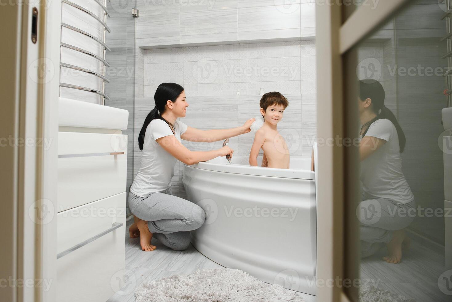 Mother washing little son in bathroom photo