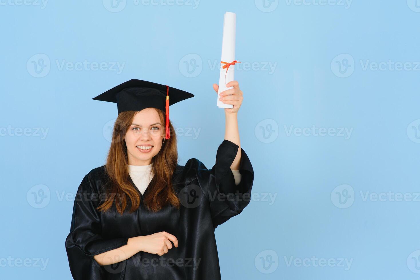 Woman graduate student wearing graduation hat and gown, on blue background photo