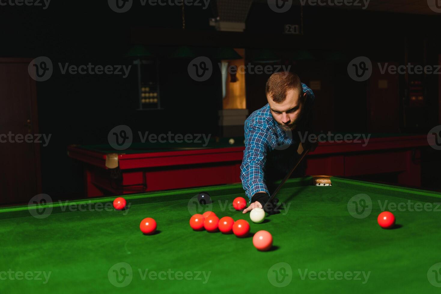 Young handsome man leaning over the table while playing snooker photo