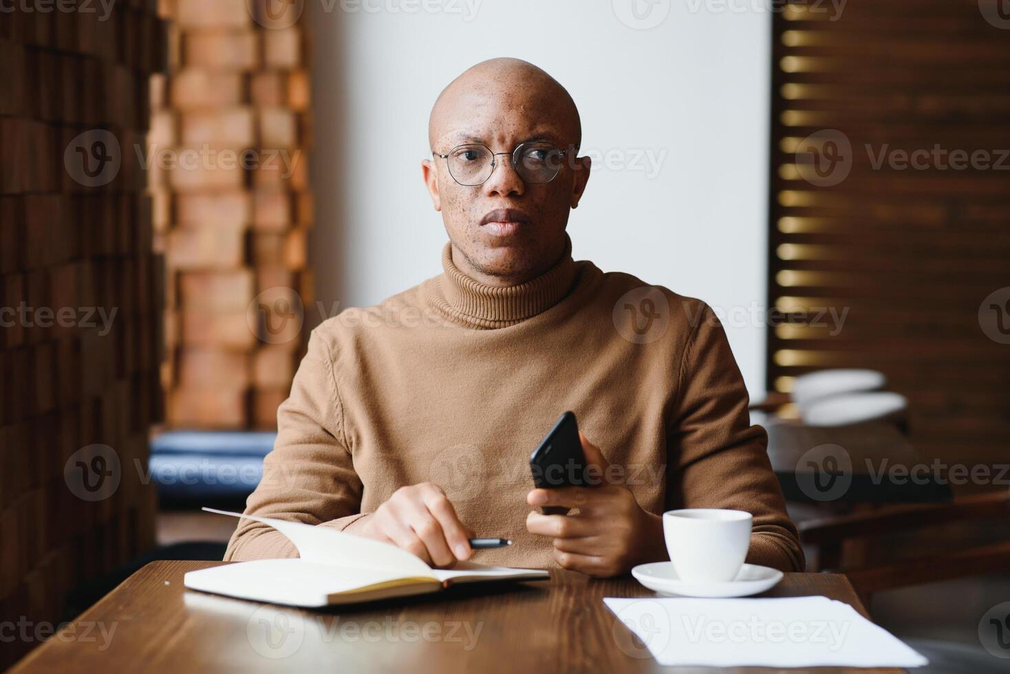 conocimiento, aprendiendo, educación y tecnología. por casualidad vestido trabajando duro un estudiante con afro peinado resolviendo matemático problemas, sentado a café mesa con libros de texto y electrónico dispositivo. foto