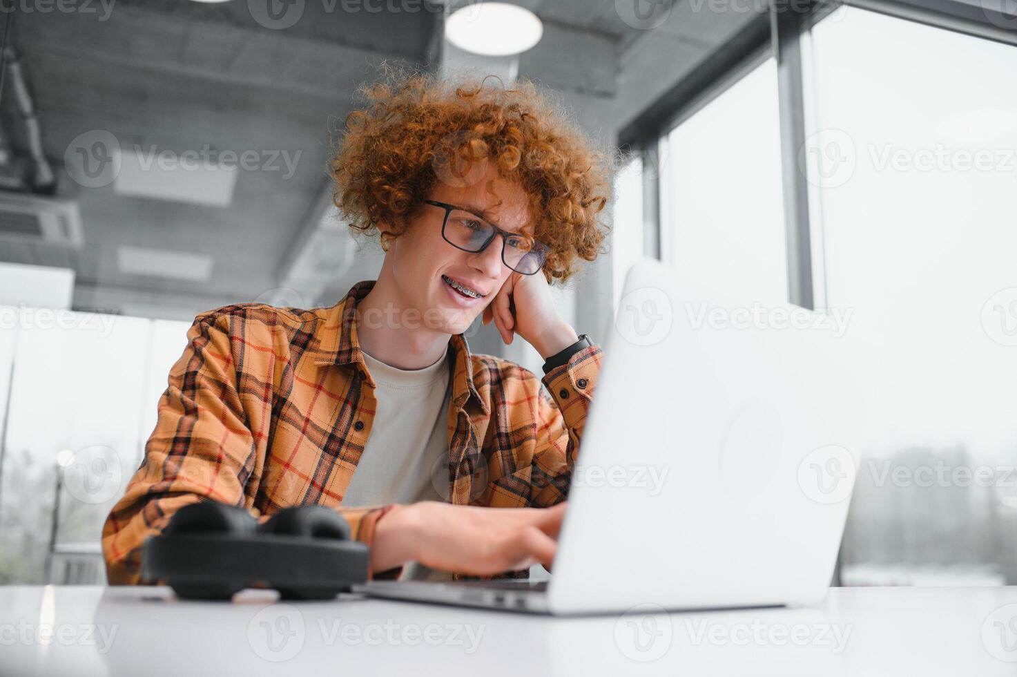 Image of amazing young man sitting in cafe while using laptop computer. photo