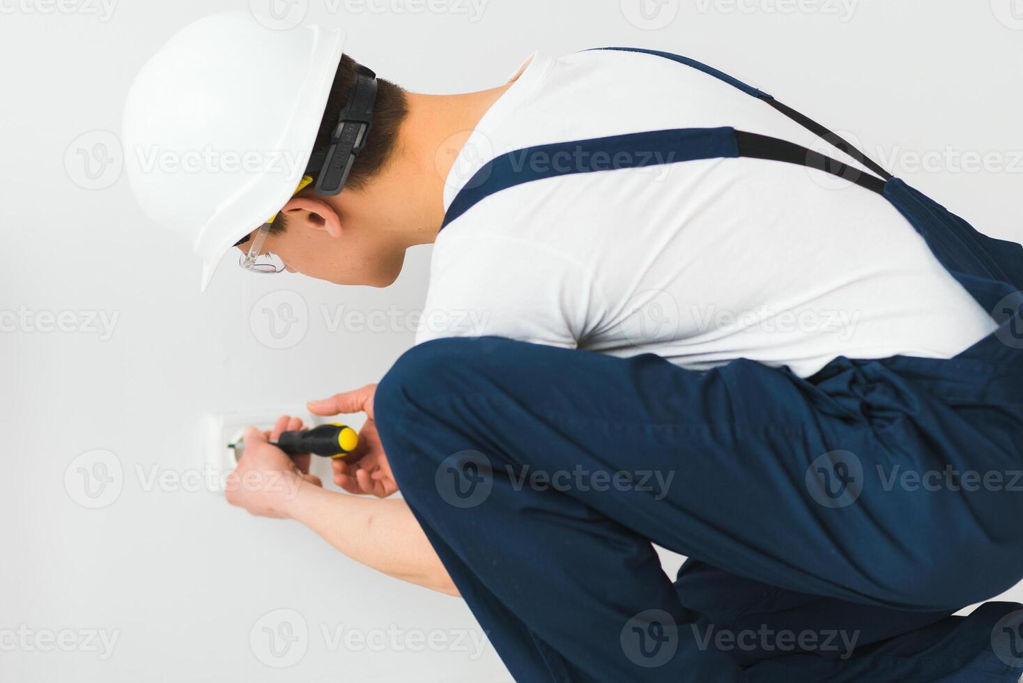 A young electrician installing an electrical socket in a new house. photo