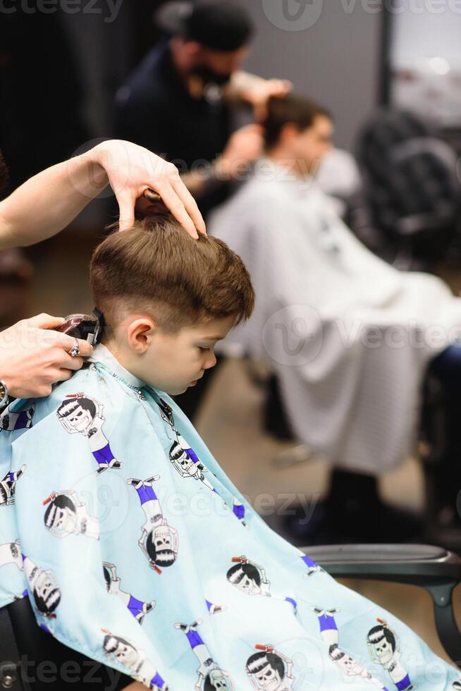 alegre caucásico chico consiguiendo peinado en barbería foto