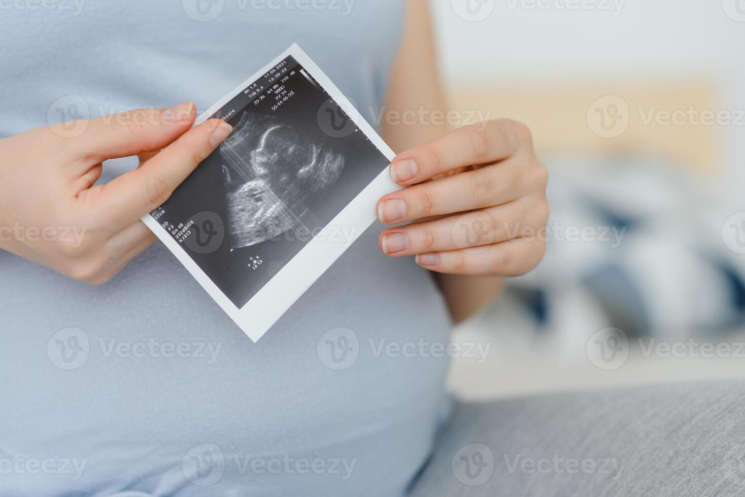 pregnant woman holding ultrasound scan on her belly photo