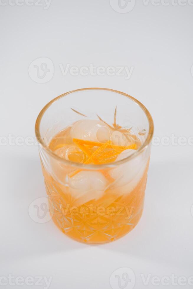 Glass of Boulevardier cocktail with big ice cube and orange zest, classic cocktail Boozy Boulevardier with Orange and Vermouth isolated on white background photo