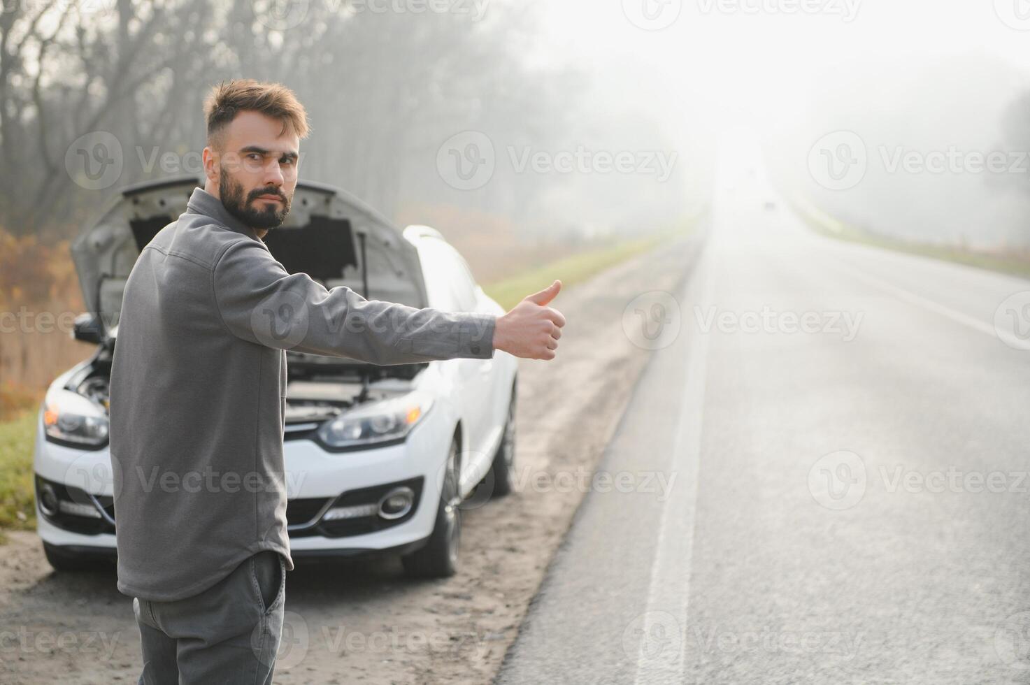 Sad driver having engine problem standing near broken car on the road. Car breakdown concept photo