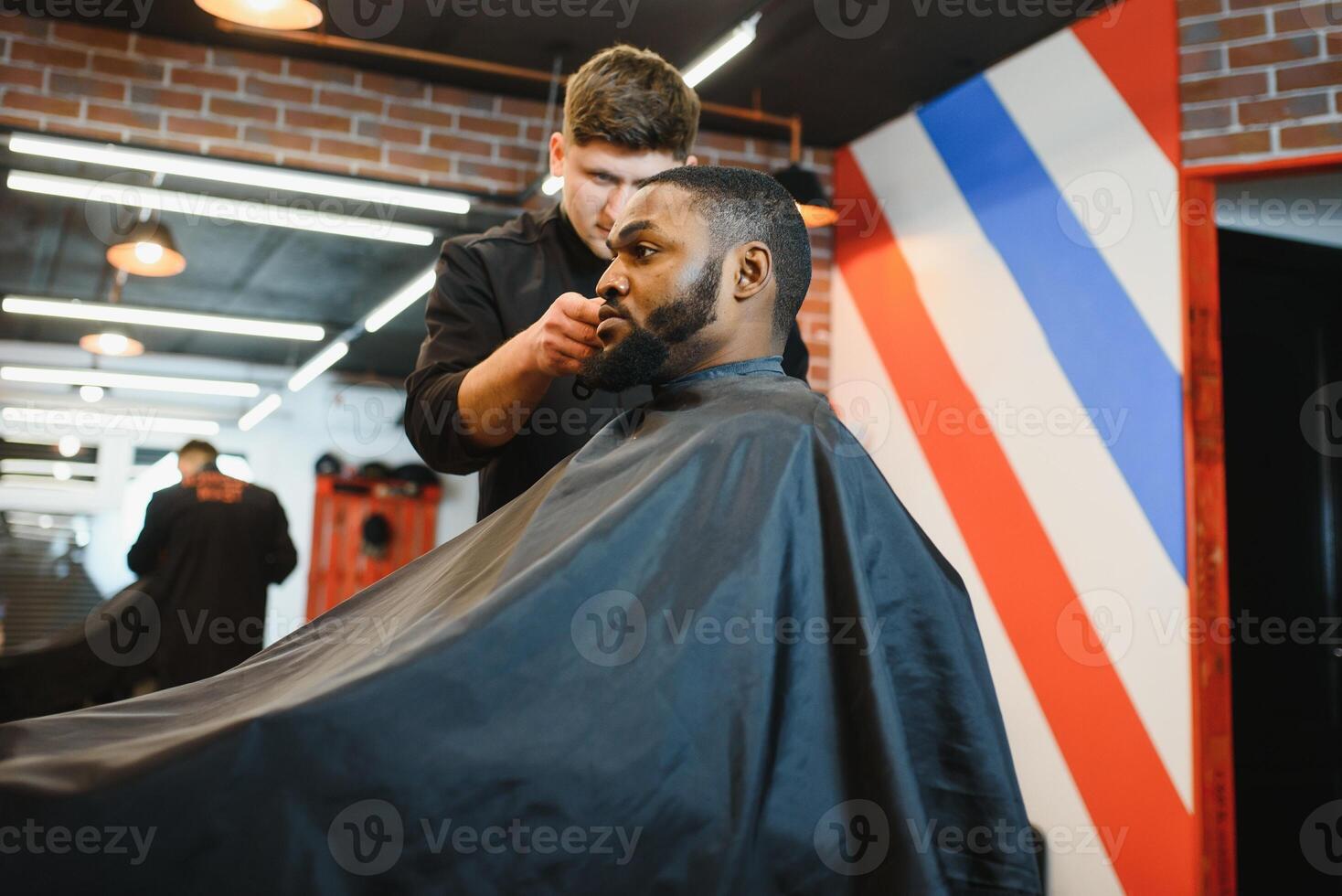 Closeup of process of trimming of hair in barber shop. Qualified barber keeping clipper in hands and correcting shape of hair to male client sitting on chair. Concept of haircut and shaving. photo