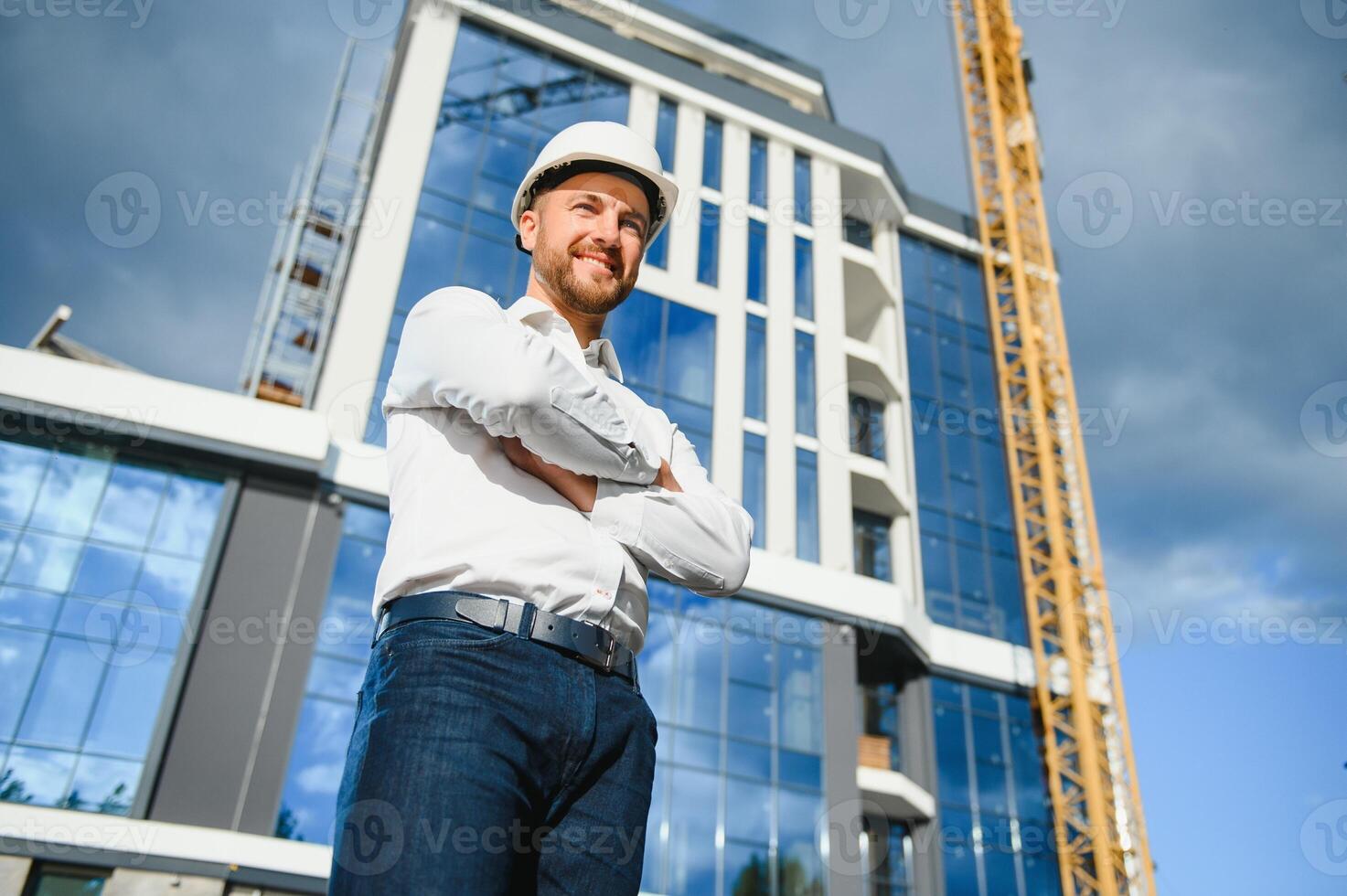 Engineer next to building cranes. Concept - large construction project. Architect directs the construction process. Drawings and tablet in the hands. photo