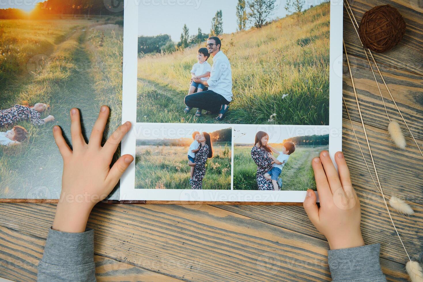 the Hand child holding a family photo album against the background of the a wooden table