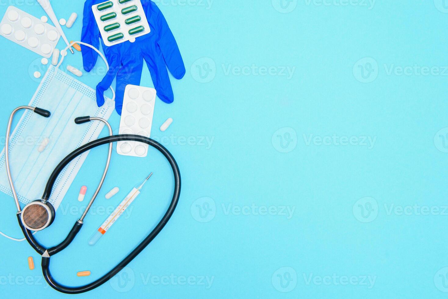 Top view of medicines, work tools and accessories doctor, nurse. Medical set - Tablets, thermometer, syringe, ampoules, adhesive plaster and statoscope on a blue background. Flat lay. photo