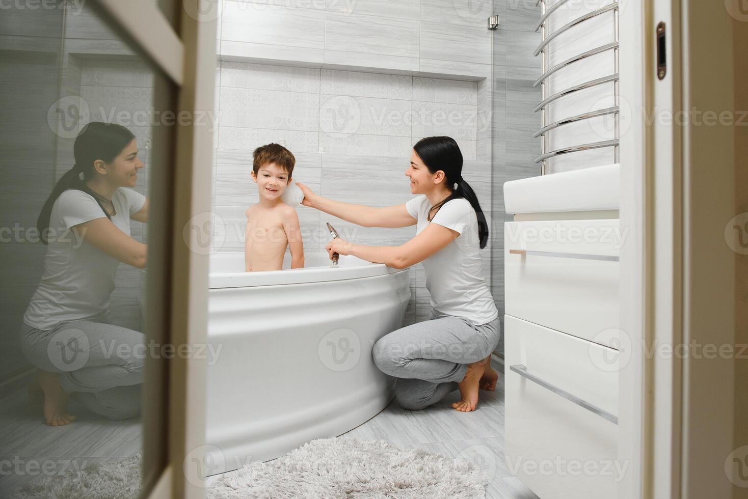 Mother washing little son in bathroom photo