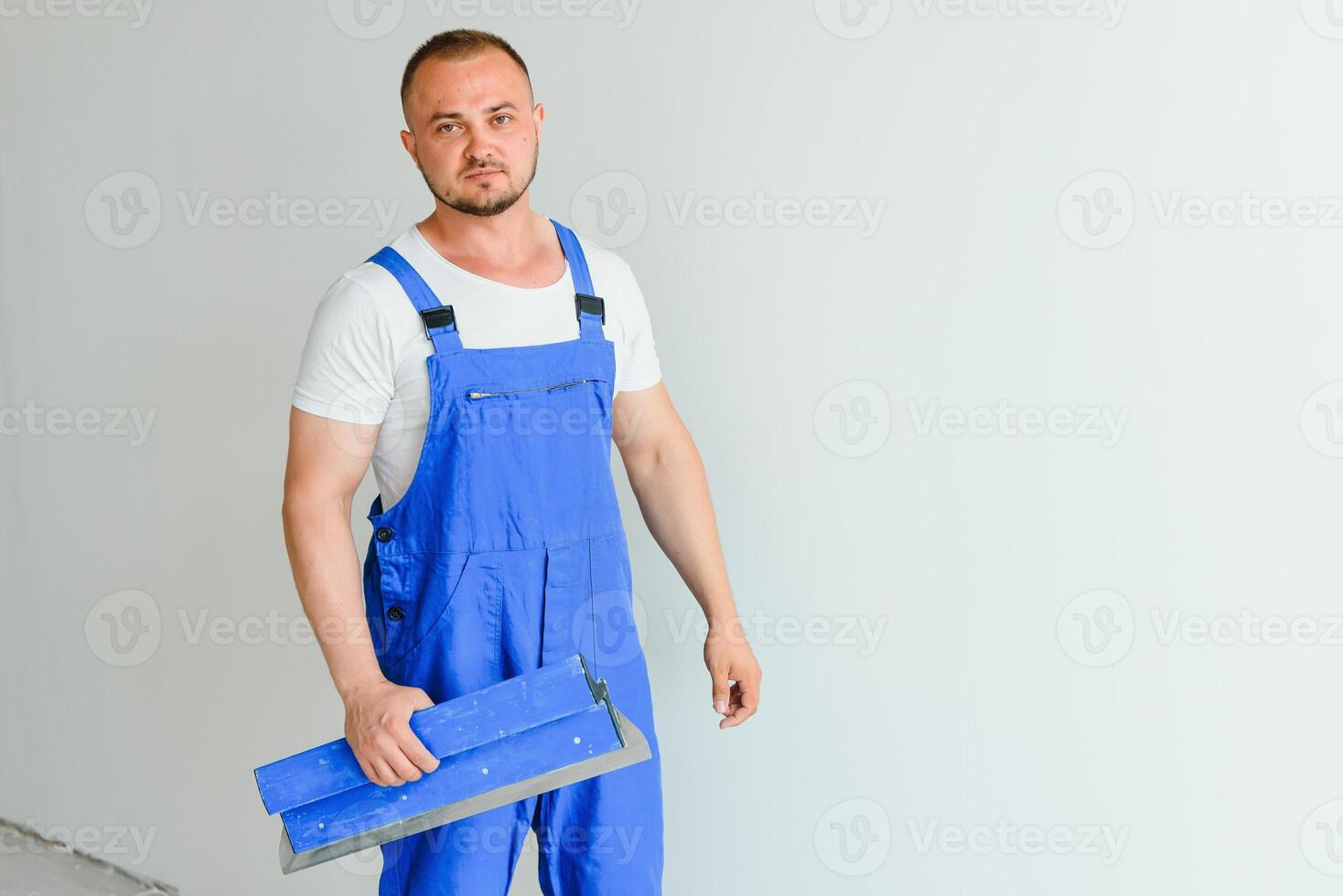 A man processes the wall with a spatula. Plasterer at work. photo