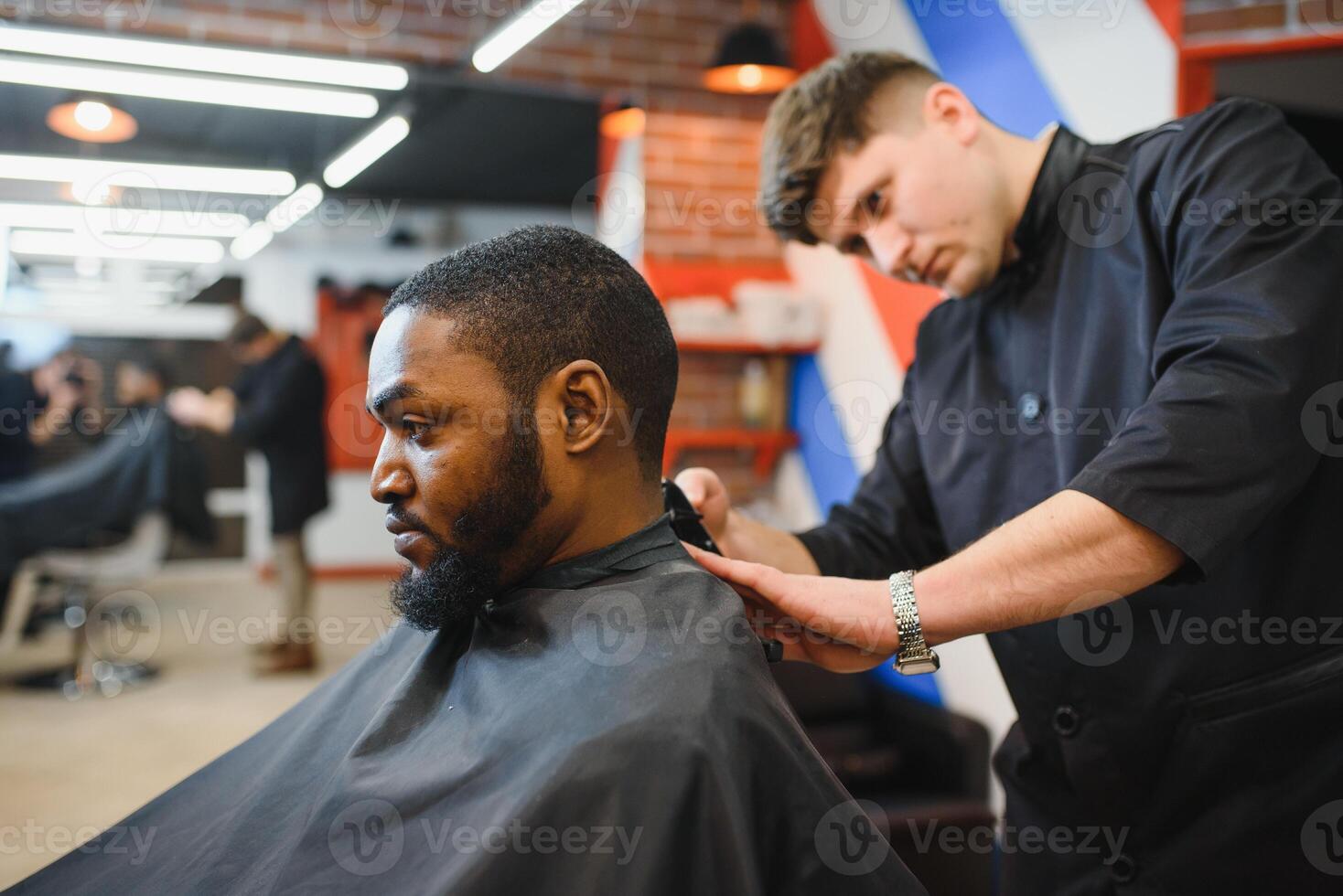 Closeup of process of trimming of hair in barber shop. Qualified barber keeping clipper in hands and correcting shape of hair to male client sitting on chair. Concept of haircut and shaving. photo