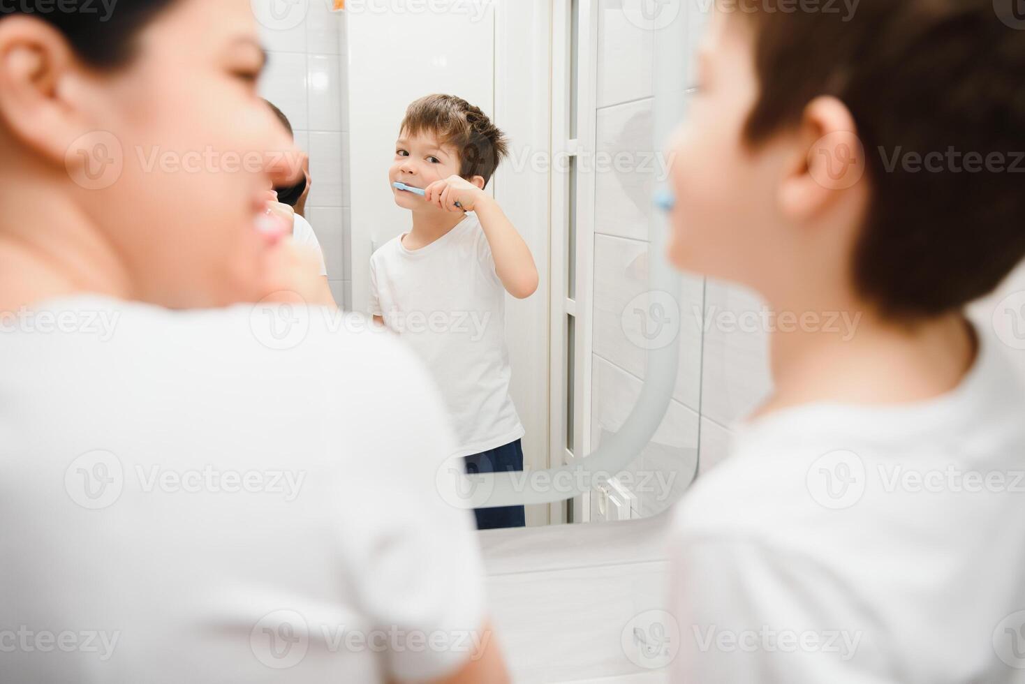 cute mother teaching kid boy teeth brushing photo