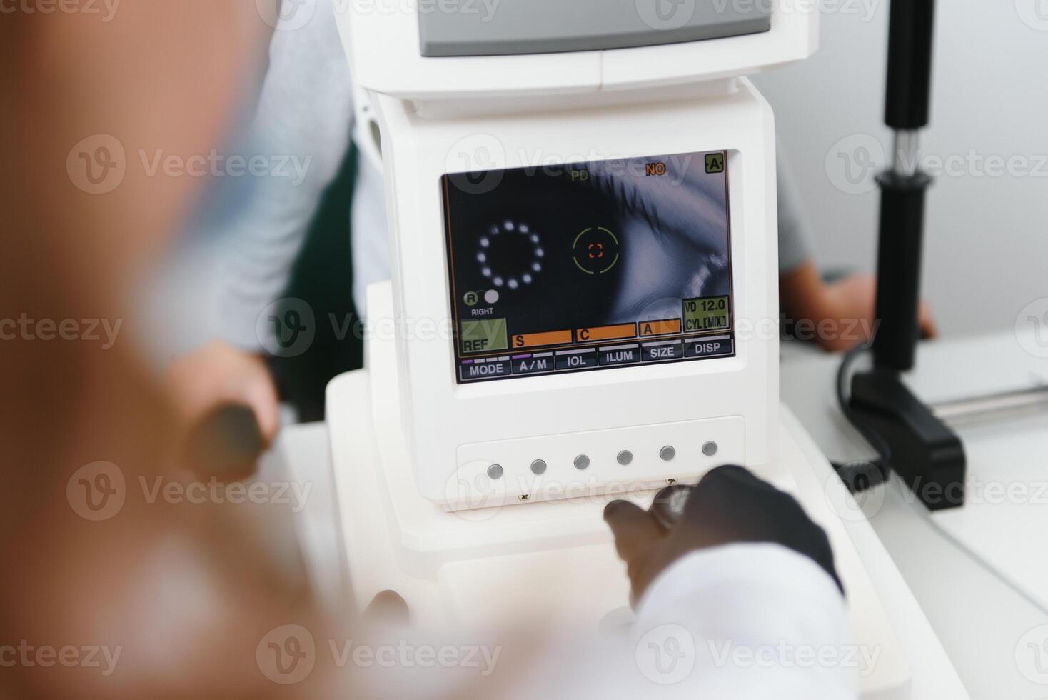 Modern medical equipment. Close up of ophthalmologist using auto refractometer while examining child eyes. photo