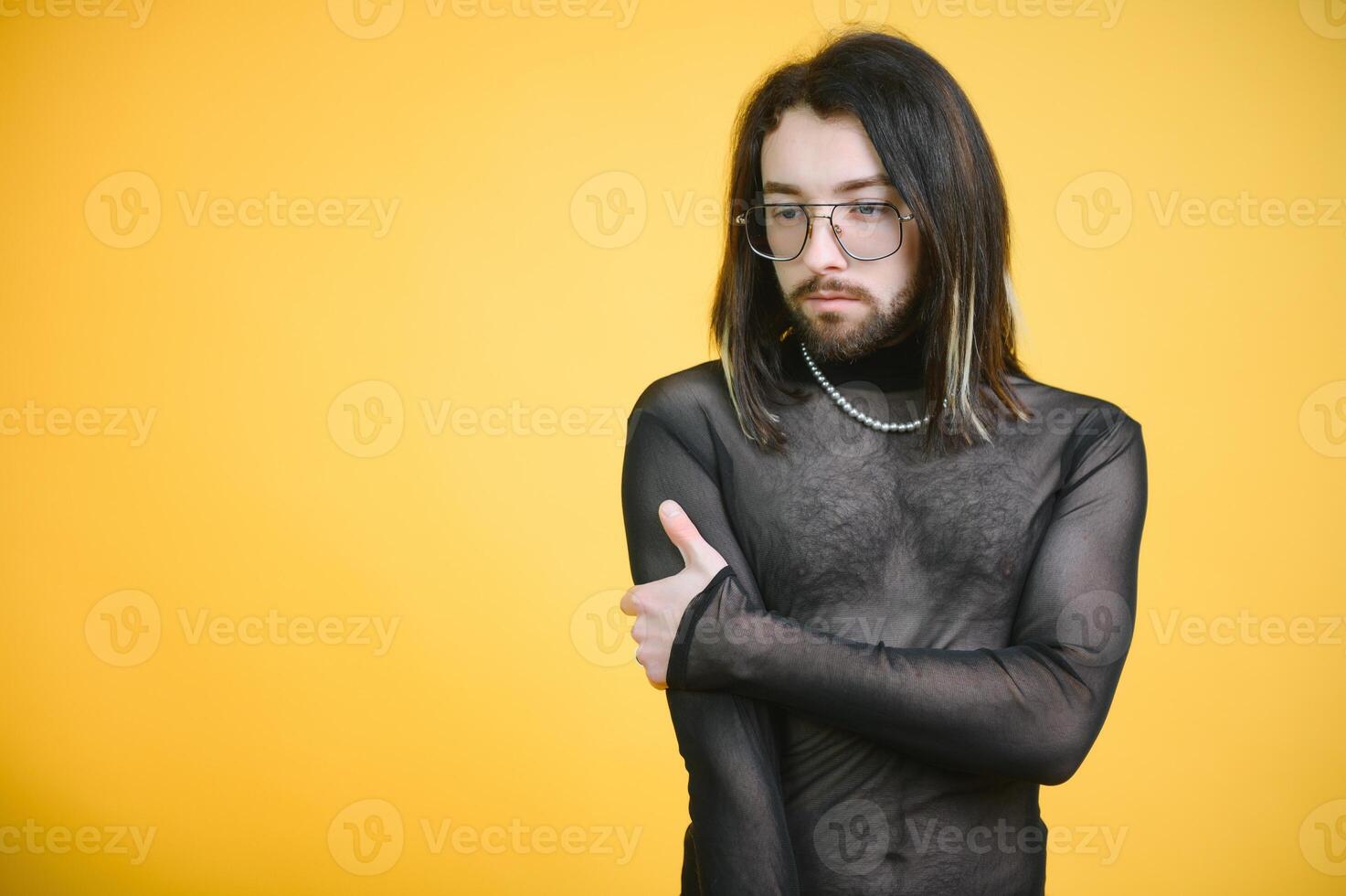 Young gay man is standing in the studio and posing for a camera. photo