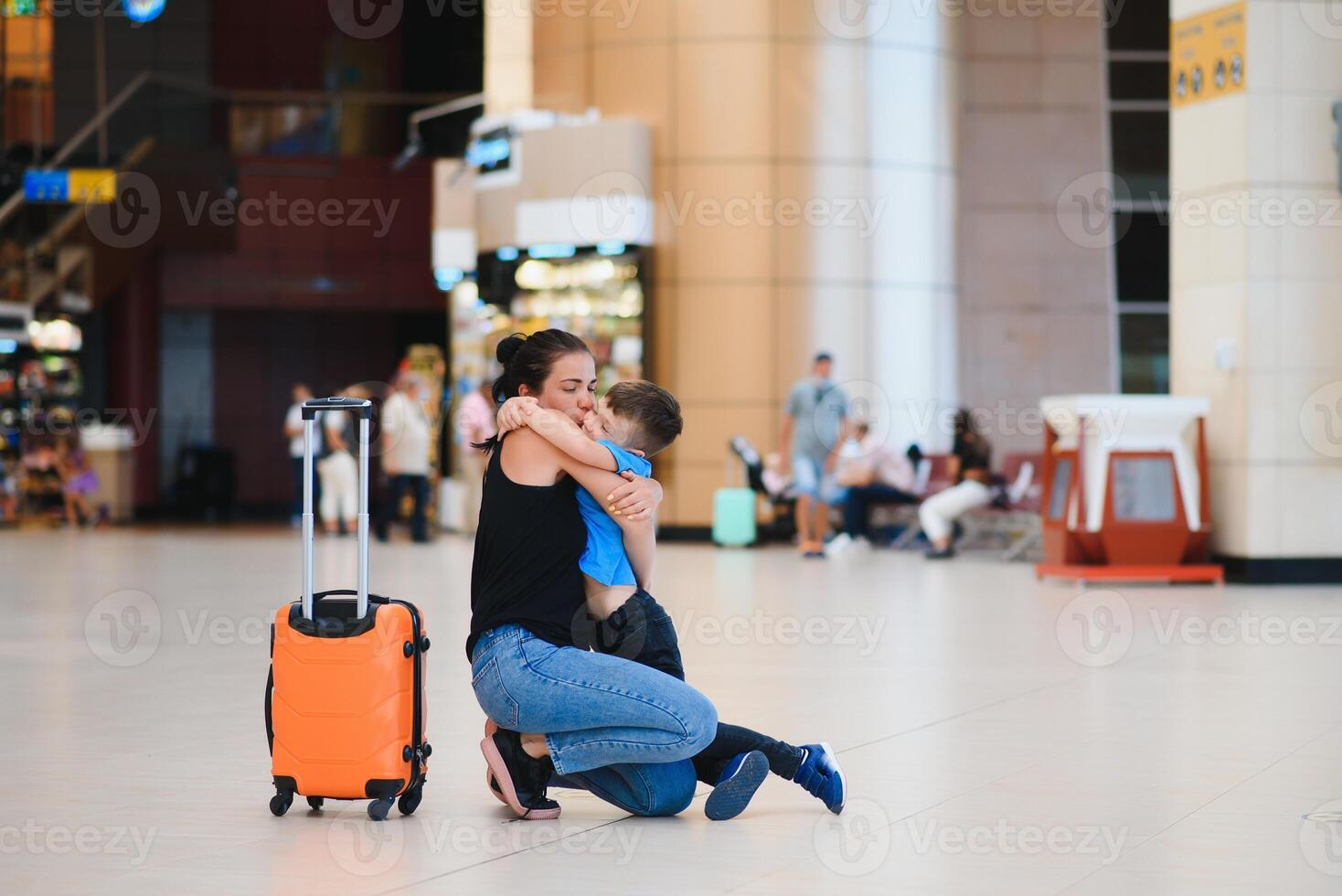 Family at airport before flight. Mother and son waiting to board at departure gate of modern international terminal. Traveling and flying with children. Mom with baby and toddler boarding airplane. photo