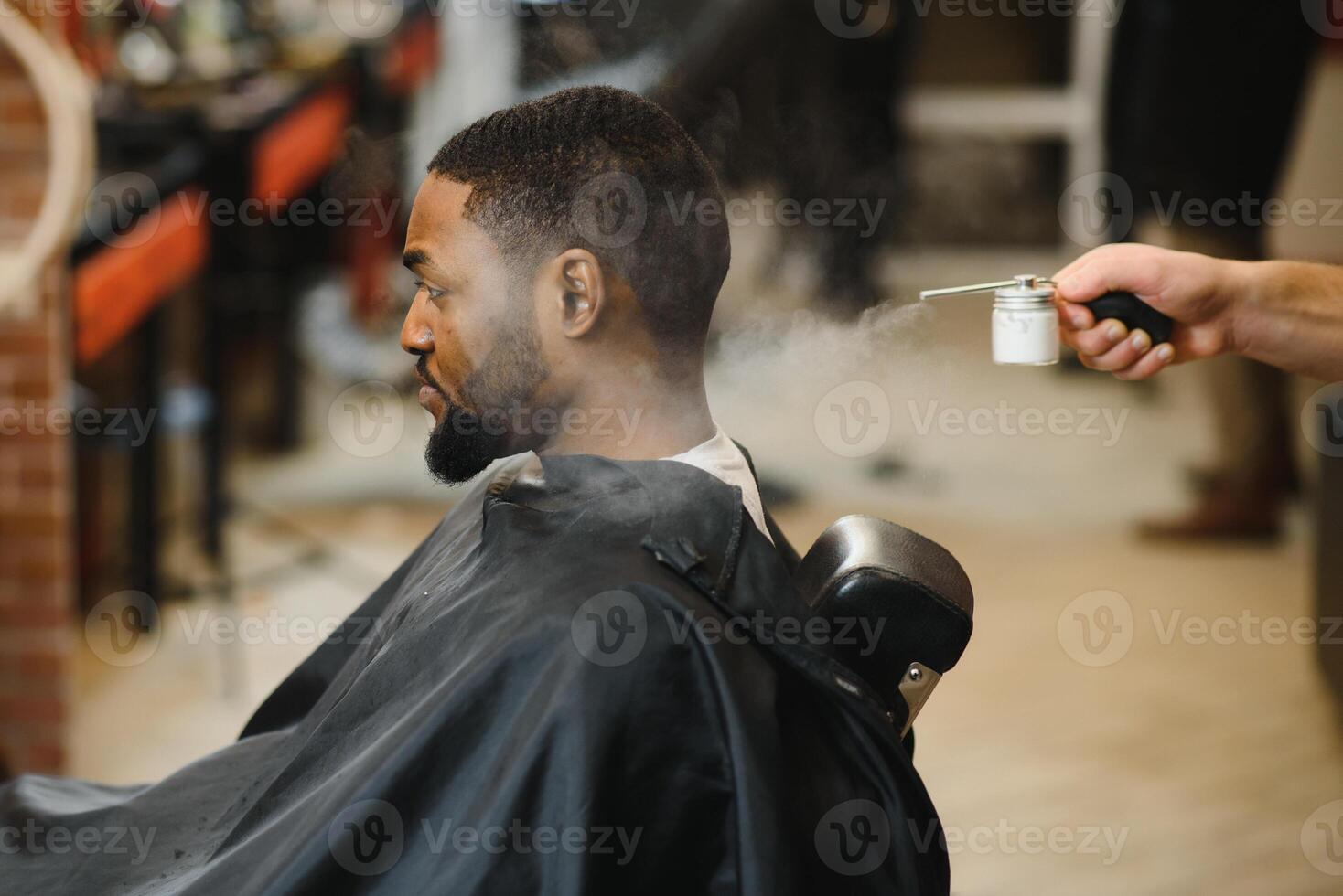 African male client getting haircut at barber shop from professional hairstylist. photo