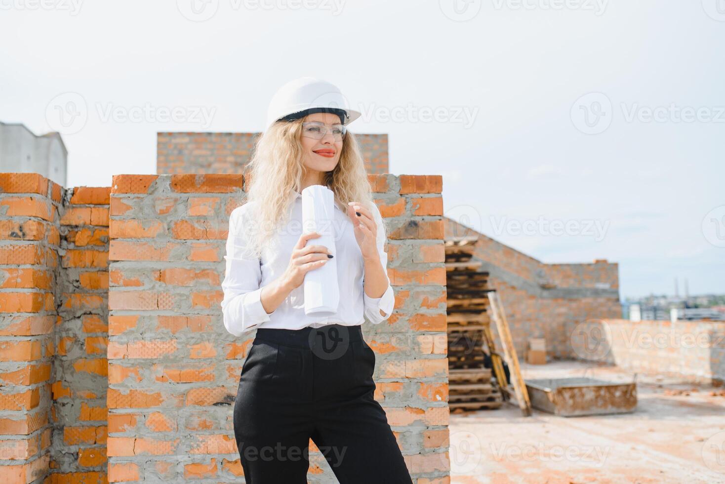 Construction engineer. Girl with construction documentation. A woman in a white hard hat against the roof of a building. Construction of a new house. photo