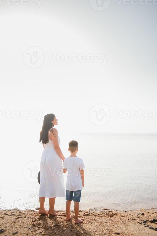 Mother and son playing on the beach at the day time. Concept of friendly family. photo