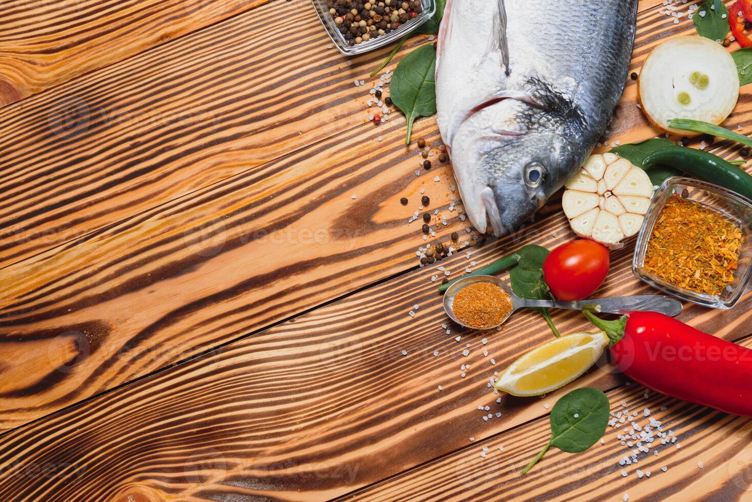 Raw fish cooking and ingredients. Dorado, lemon, herbs and spices. Top view with copy space on table photo