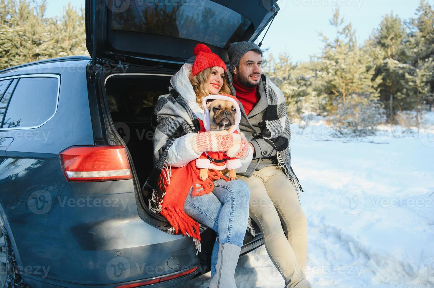 Happy couple sitting in open car back, having stop off. Romantic traveling concept. Winter forest. photo