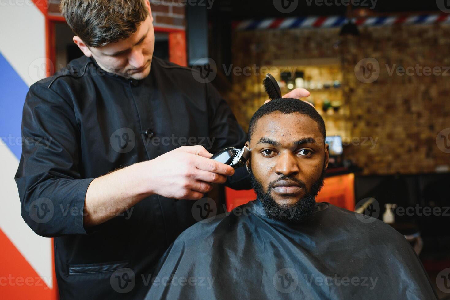 Closeup of process of trimming of hair in barber shop. Qualified barber keeping clipper in hands and correcting shape of hair to male client sitting on chair. Concept of haircut and shaving. photo