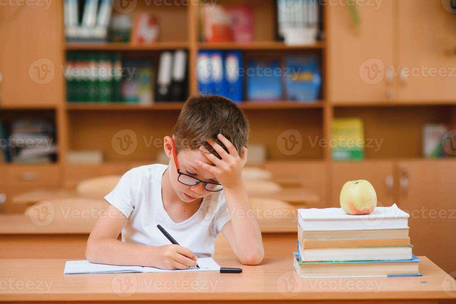 Elementary school boy at classroom desk trying to find new ideas for schoolwork. photo