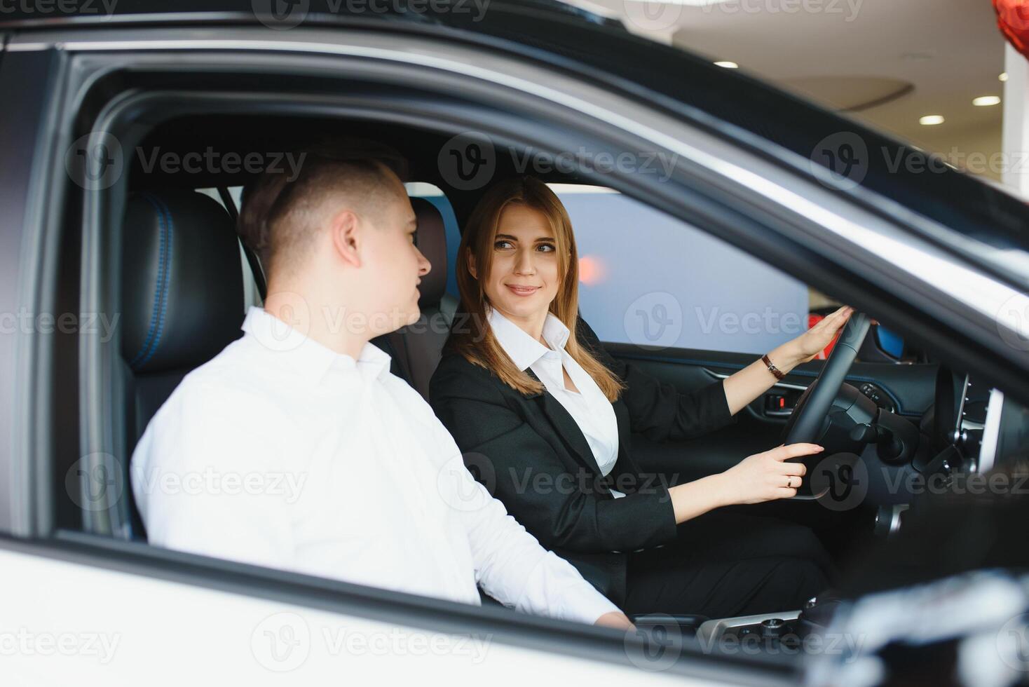 Young beautiful happy couple buying a car. Husband buying car for his wife in a salon. Car shopping concept photo