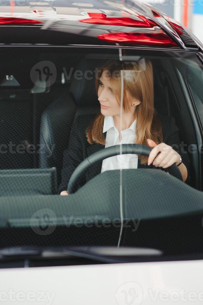 foto de contento joven mujer sentado dentro su nuevo coche. concepto para coche alquiler.