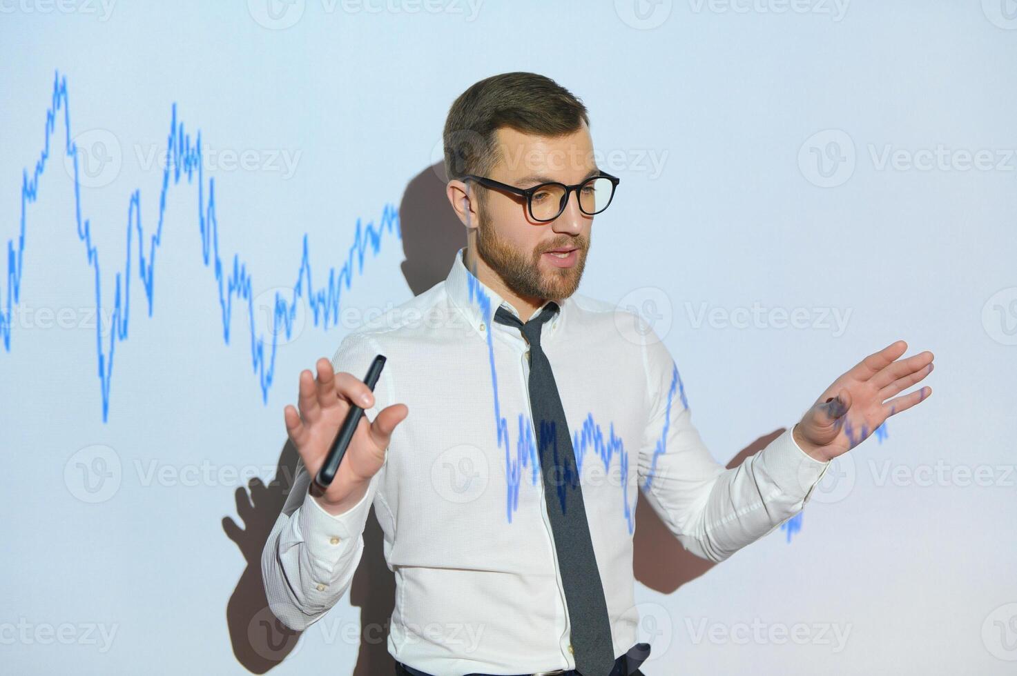 Man is standing near projector and showing graphs and business graphs. photo