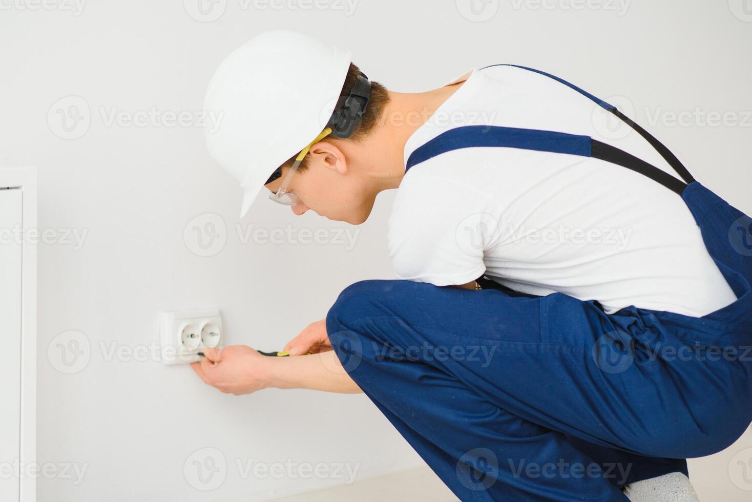 A young electrician installing an electrical socket in a new house. photo