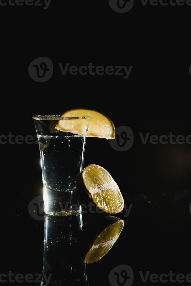 Tequila with lime and salt on black background photo