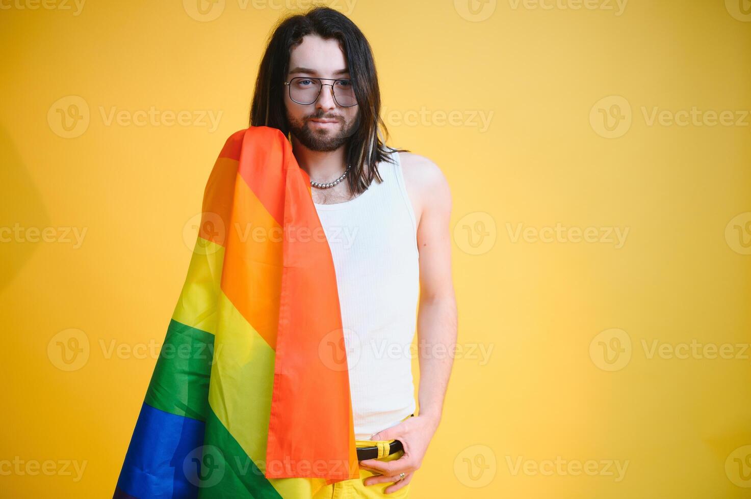 Gay man hold rainbow striped flag isolated on colored background studio portrait. People lifestyle fashion lgbtq concept photo