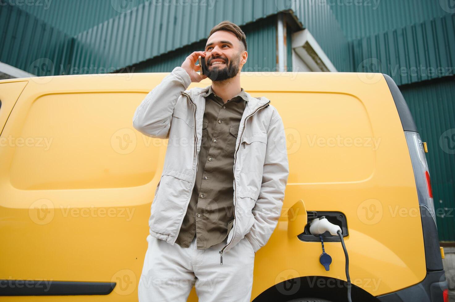 Happy young adult man charging automobile battery from small public station. photo