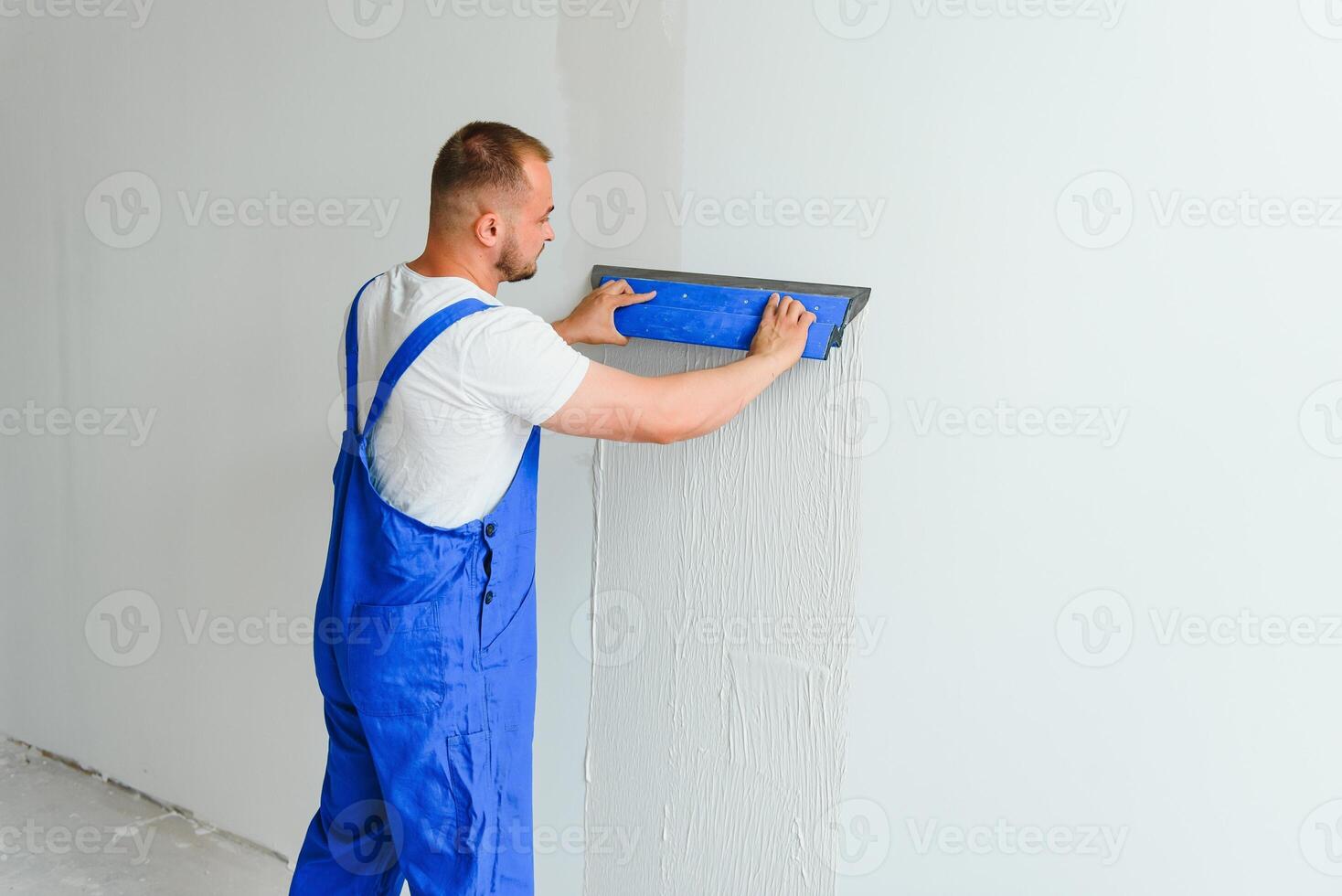 A man processes the wall with a spatula. Plasterer at work. photo
