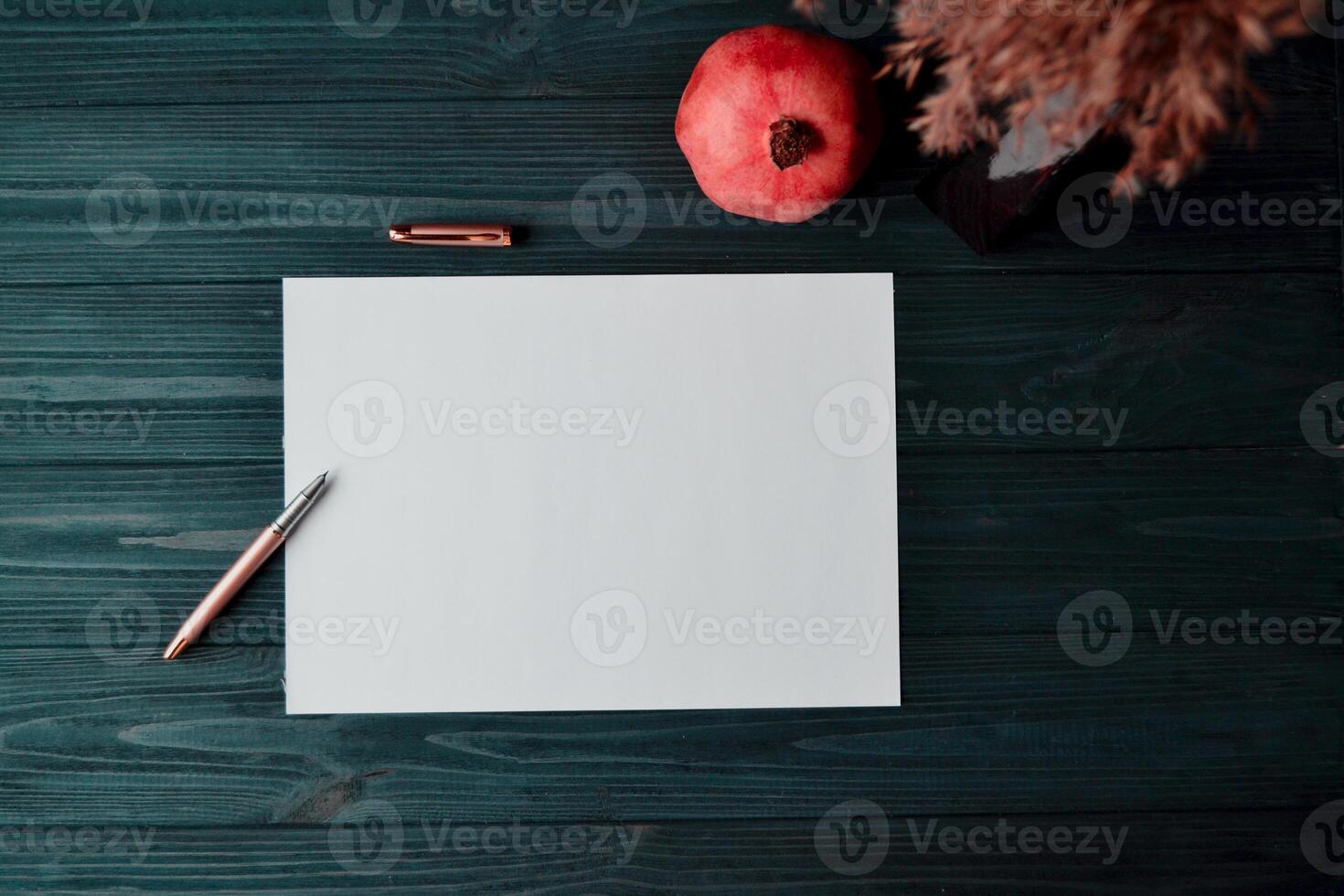 The sheet of white paper with pen and garnet on the dark blue wooden desk. Vintage background with place for text. photo