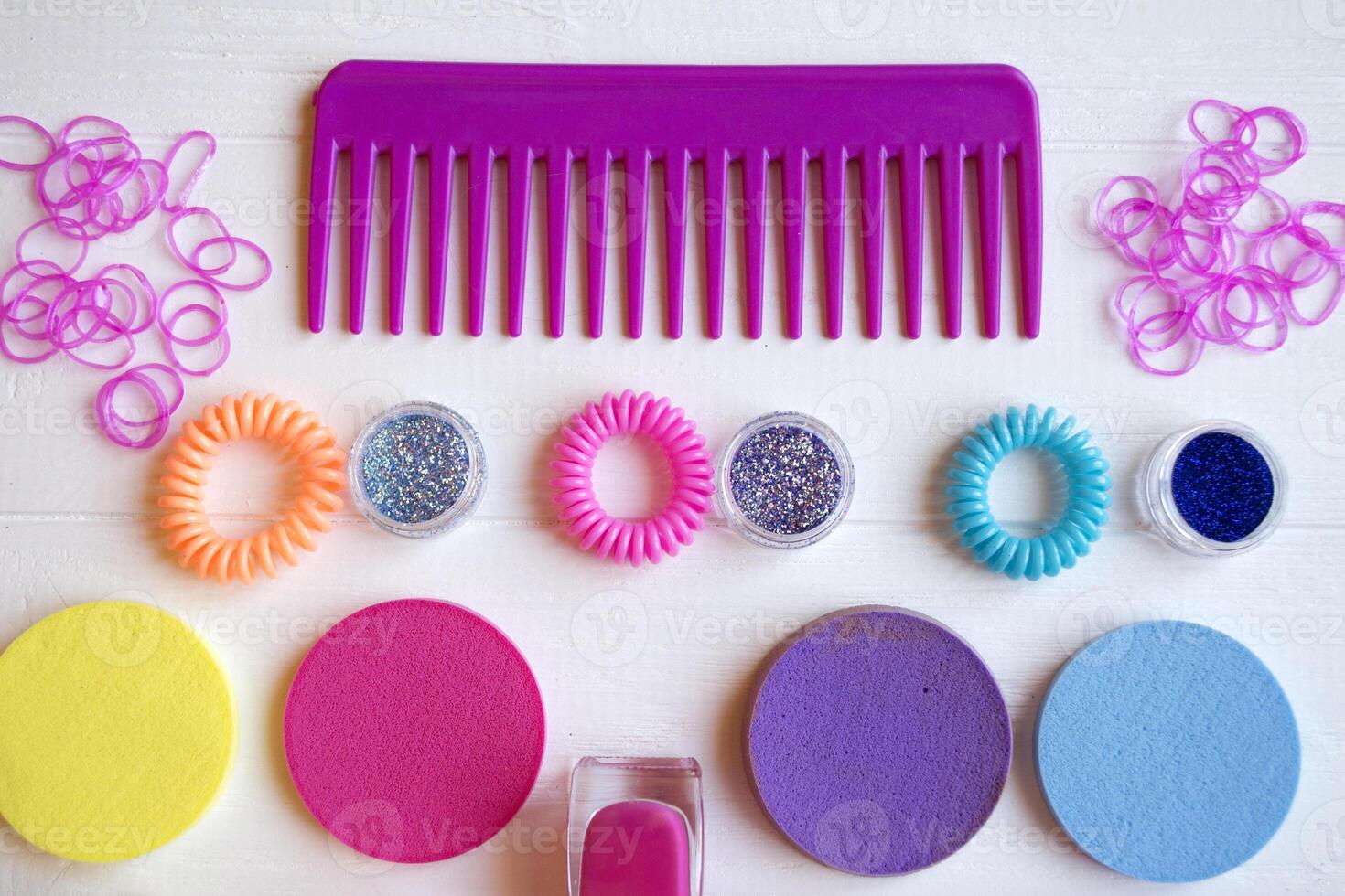 Colorful and bright cosmetics. Beauty care tools. Beauty salon. Girl's paradise. Nail polishes, sequins, pink hair bands and comb on the white wooden desk. Bright still life of beauty instruments. photo