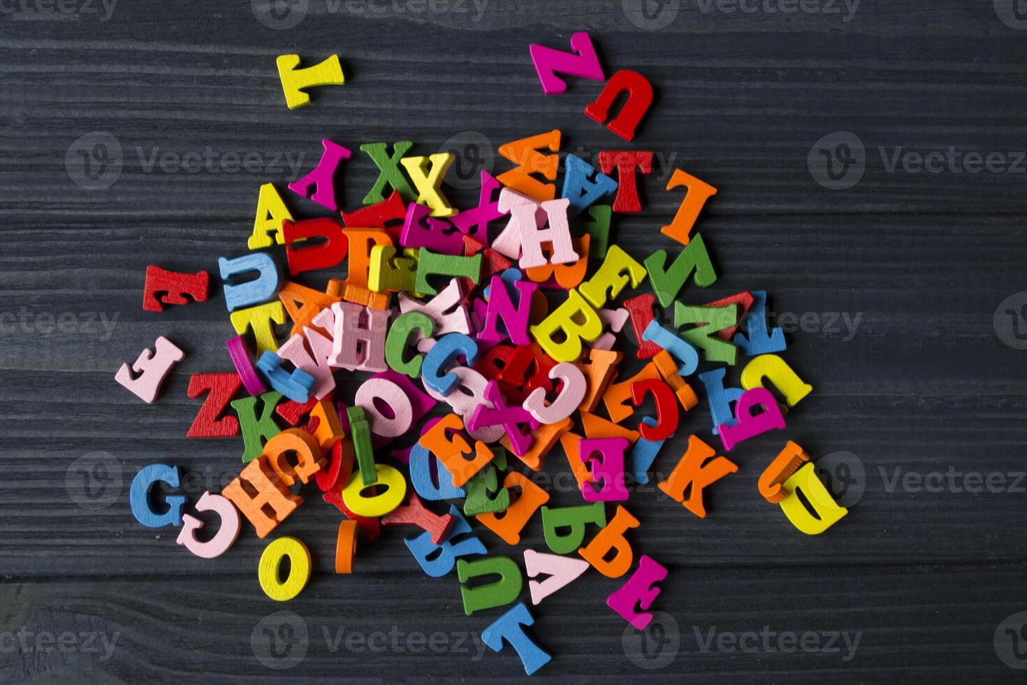 Multicolor letters on a dark blue wooden background. Colorful wooden alphabet on a table. photo