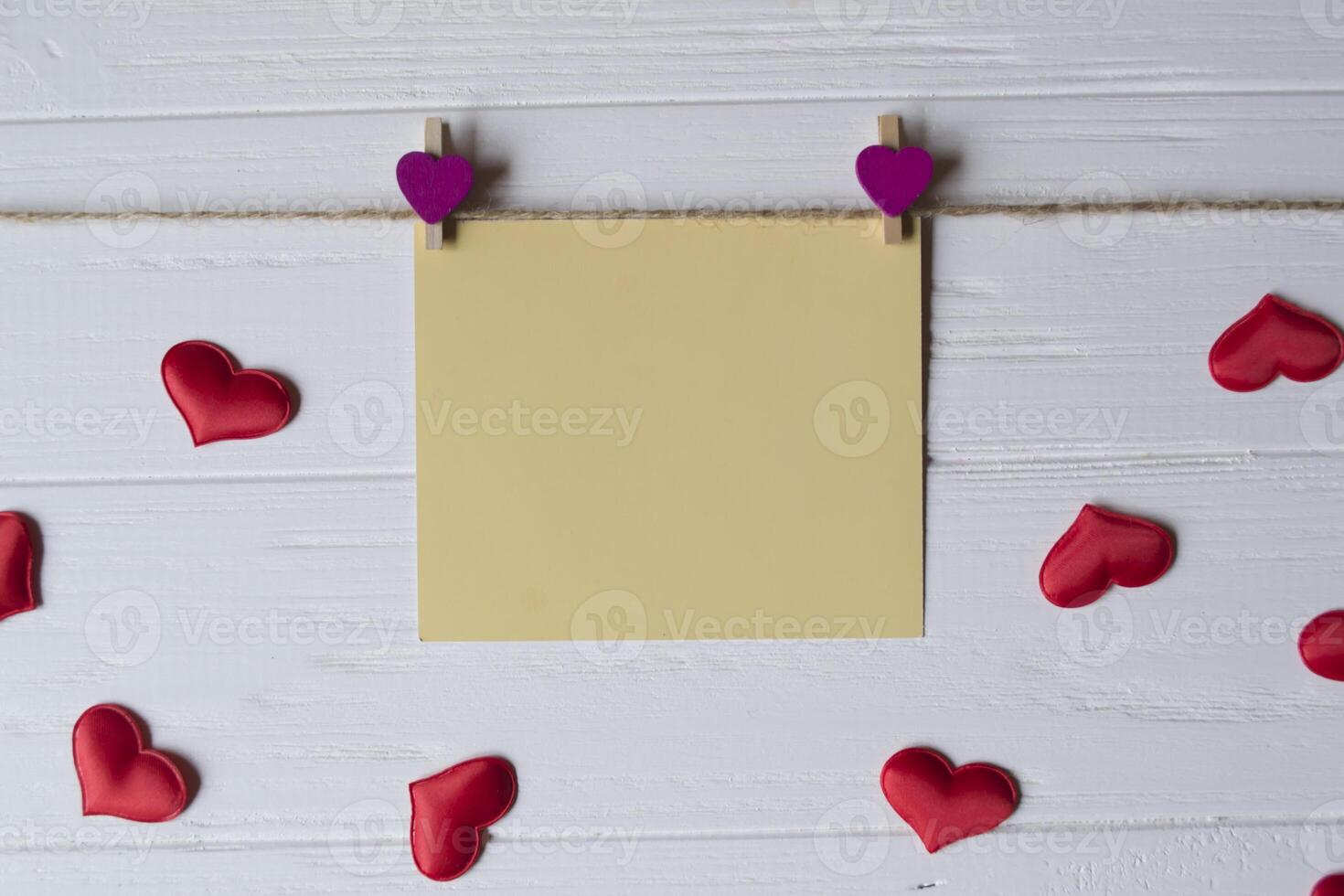 Yellow memo sheet fastened with a decorative pin on a white wooden board. photo