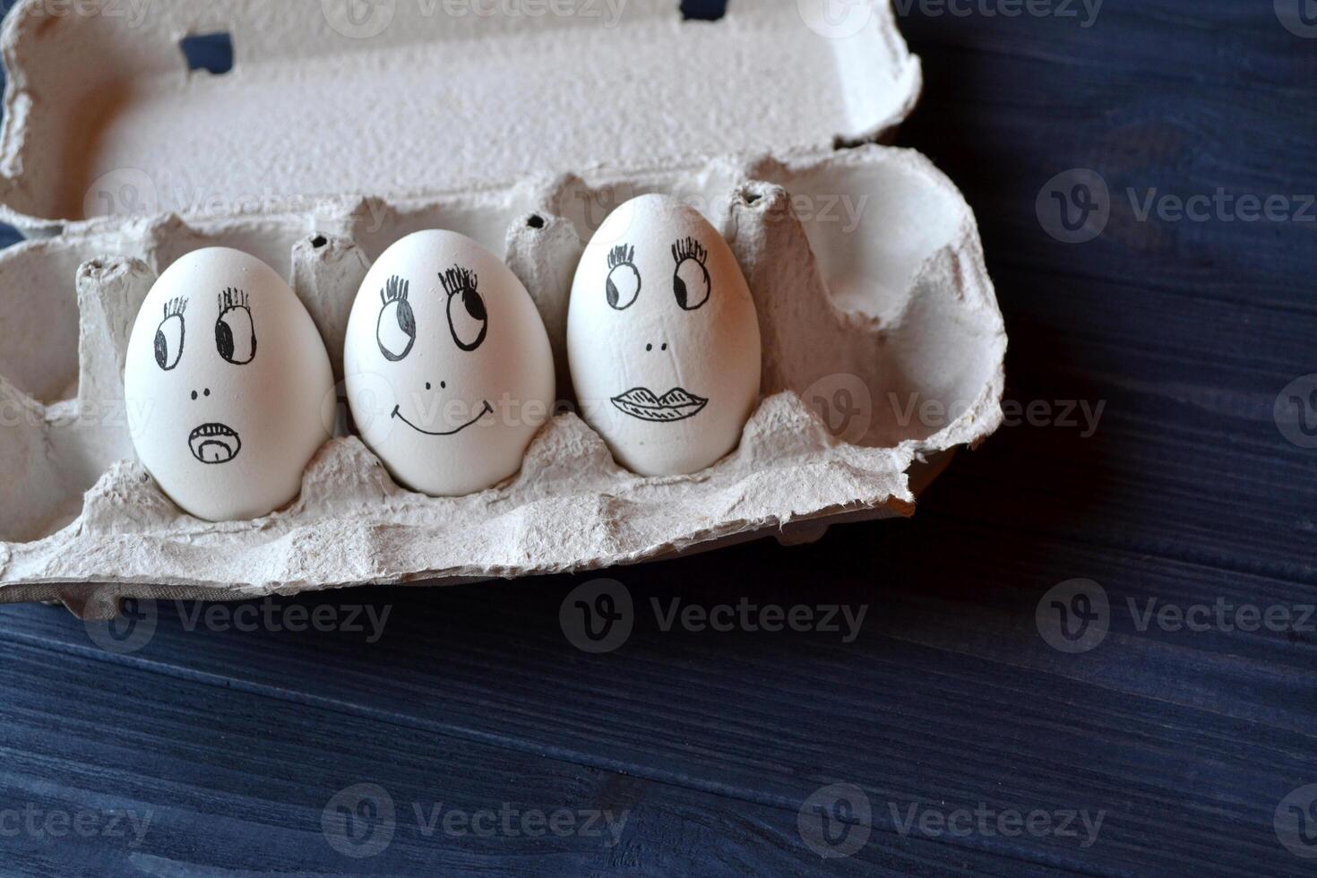 Eggs with a faces in a container box on the wooden table. Creative easter background. Happy easter day. photo