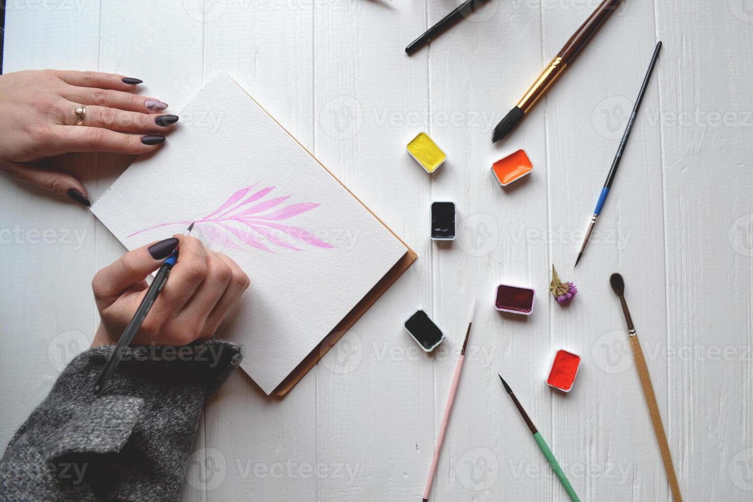 mujer pinturas en un bloc de dibujo. herramientas para pintura en el blanco de madera escritorio. pintor trabajar. foto