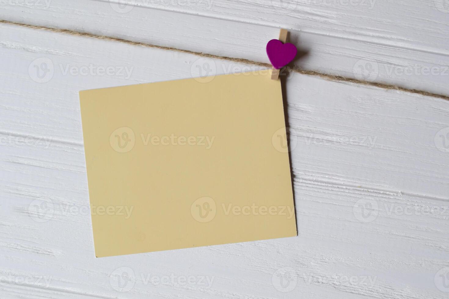 Yellow memo sheet fastened with a decorative pin on a white wooden board. photo