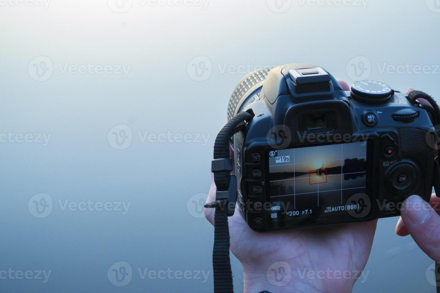 Sunset in the camera. Photographer makes a photo of landscape.