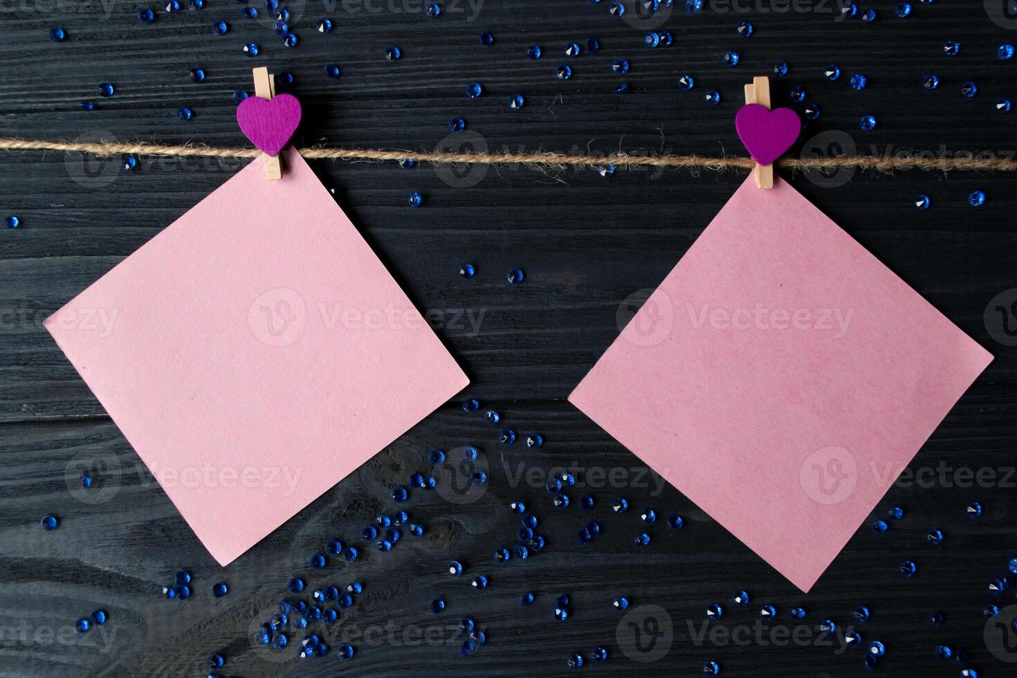 Pink memo sheets fastened with a decorative pin on a dark blue wooden board. photo