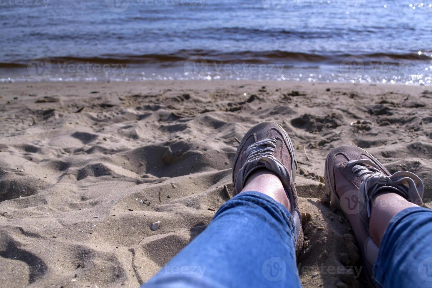 Female legs in sneakers on a sand. Relax on the beach. photo