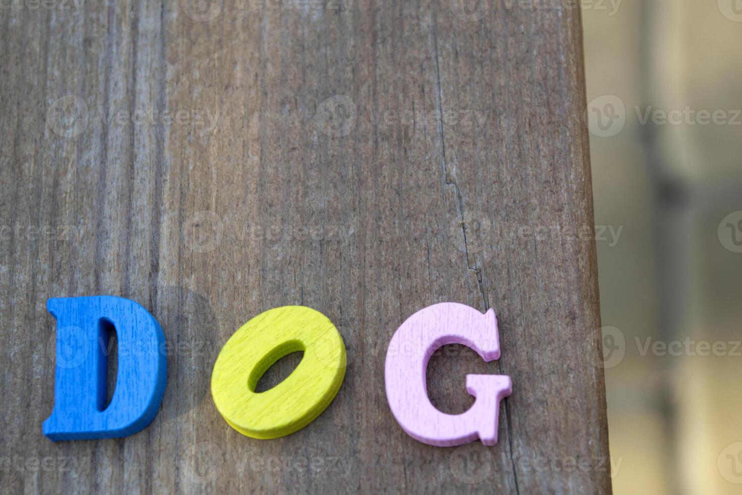 Multicolor letters on a dark blue wooden background. The word dog from colorful wooden letters on a table. photo